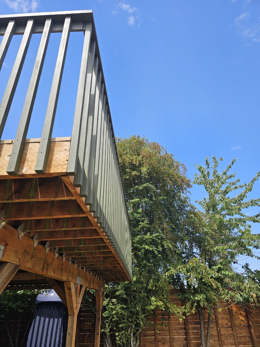 Elevated deck build with painted railings against a blue sky